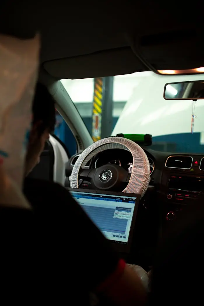 services-01 Mechanic inside car using laptop for diagnostics. Ideal for automotive and technology themes.