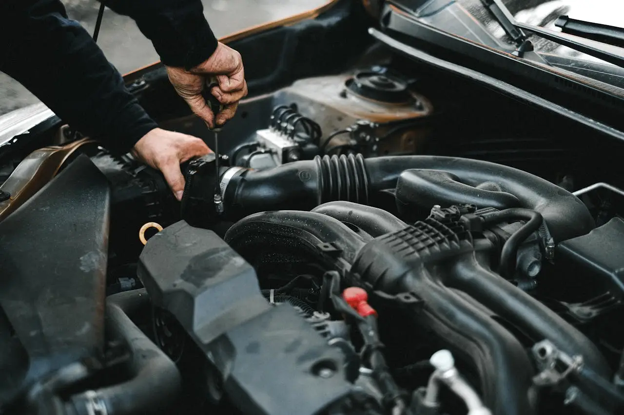 heros-img Close-up of a mechanic working on a car engine. Ideal for auto repair themes.