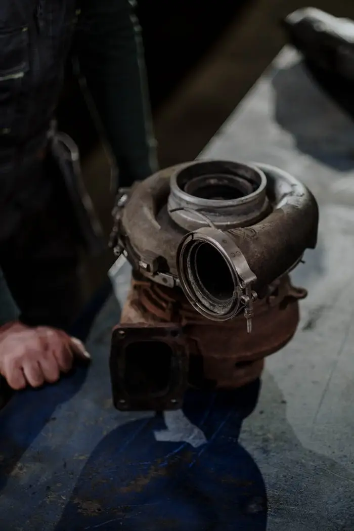 about-us Close-up of a worn turbocharger on a workbench in an auto repair shop.